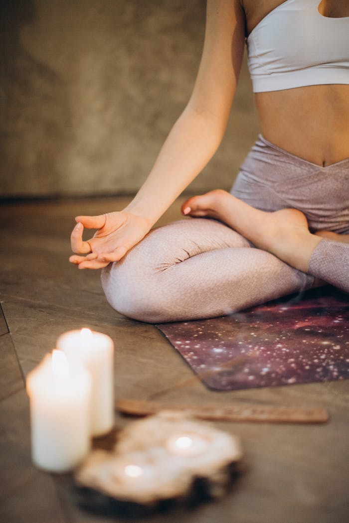 testimonial-img A woman practicing yoga indoors in lotus pose with candles creating a calming atmosphere.